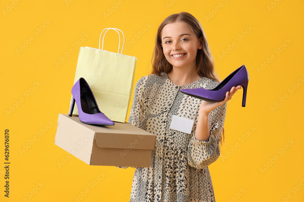 Female seller with stylish heels and shopping bag on yellow background