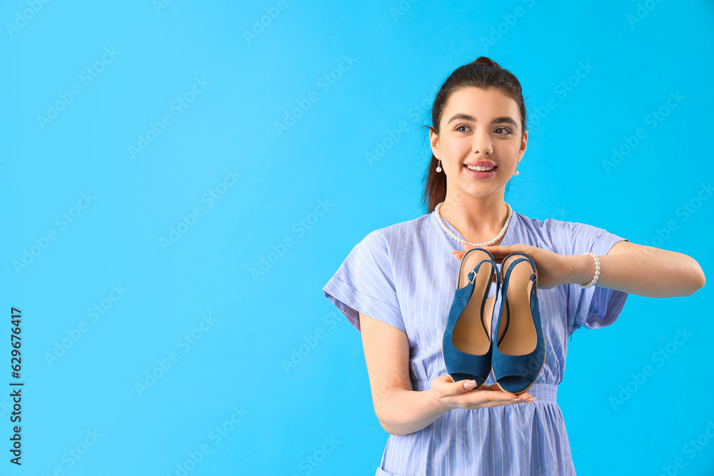 Young woman with stylish shoes on blue background