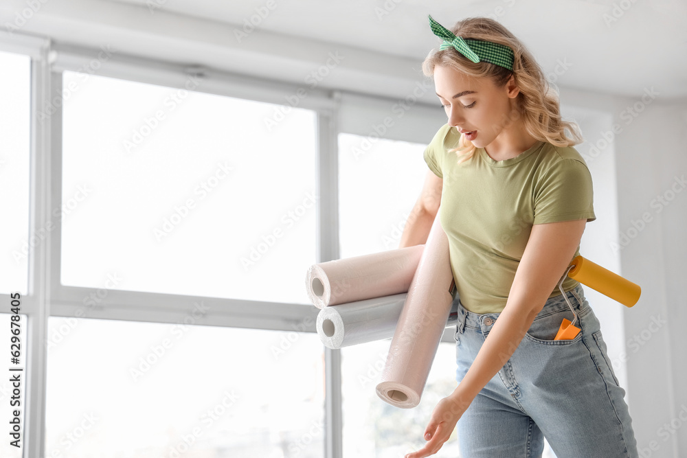 Young woman with wallpaper rolls at home