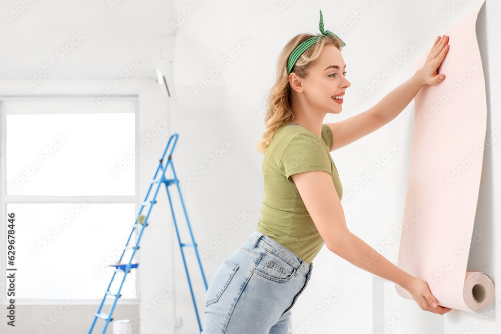 Young woman with wallpaper roll at home