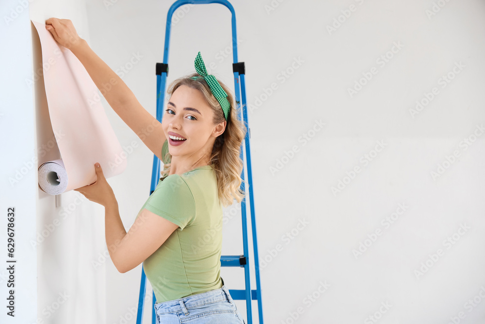 Young woman with wallpaper roll at home