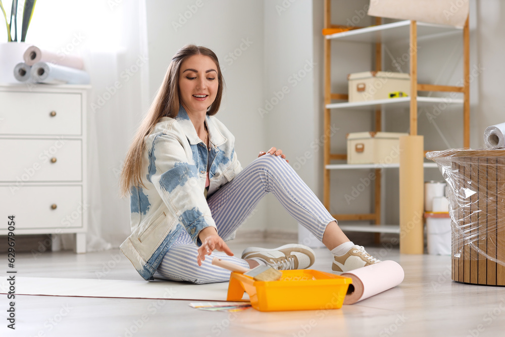 Young woman gluing wallpaper at home