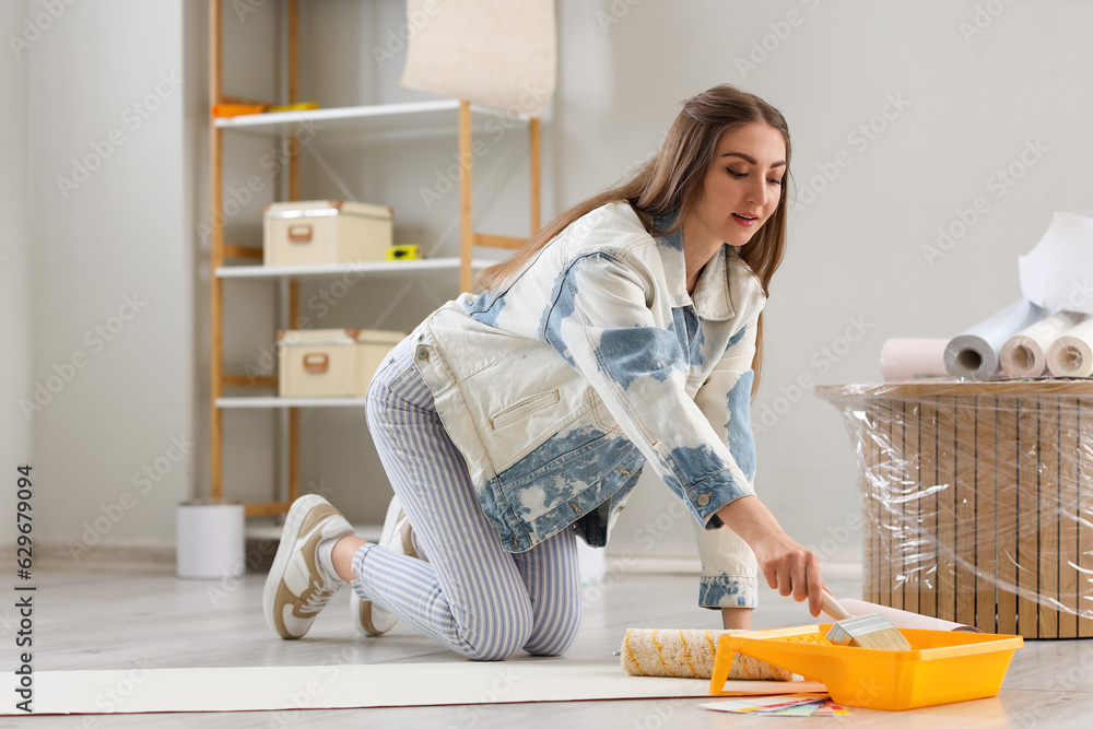 Young woman gluing wallpaper at home