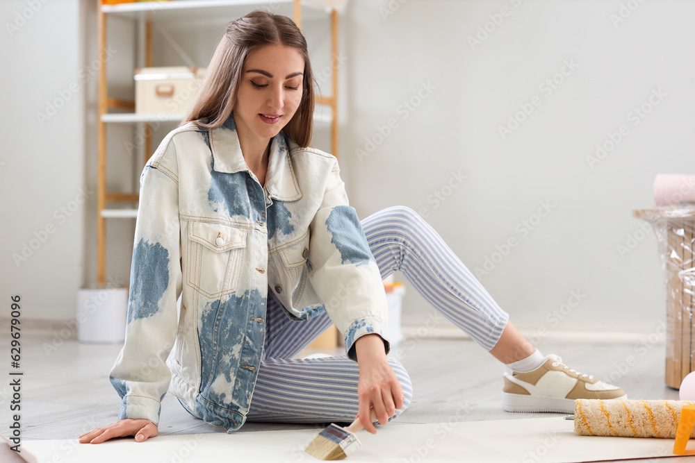 Young woman gluing wallpaper at home