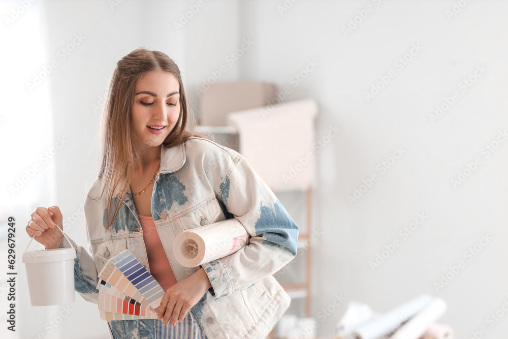 Young woman with wallpaper, glue and color palettes at home