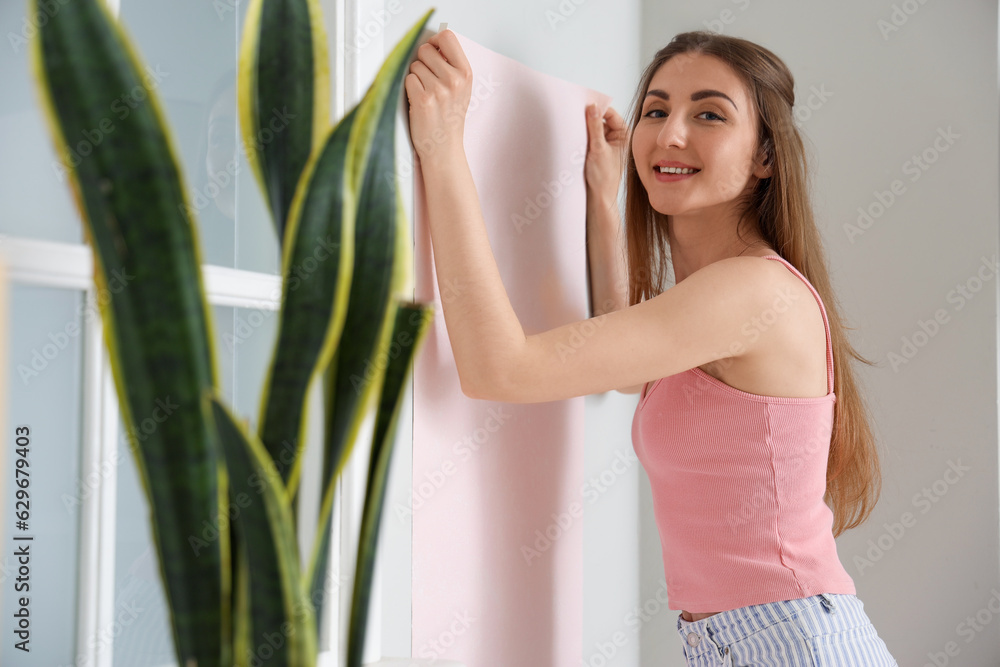 Young woman with wallpaper roll at home