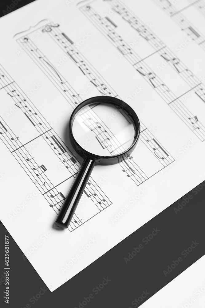 Magnifier with music sheet on black and white background