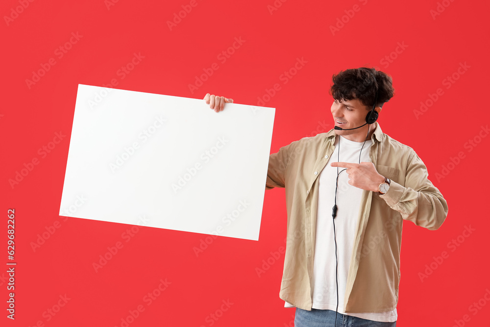 Male technical support agent with blank poster on red background