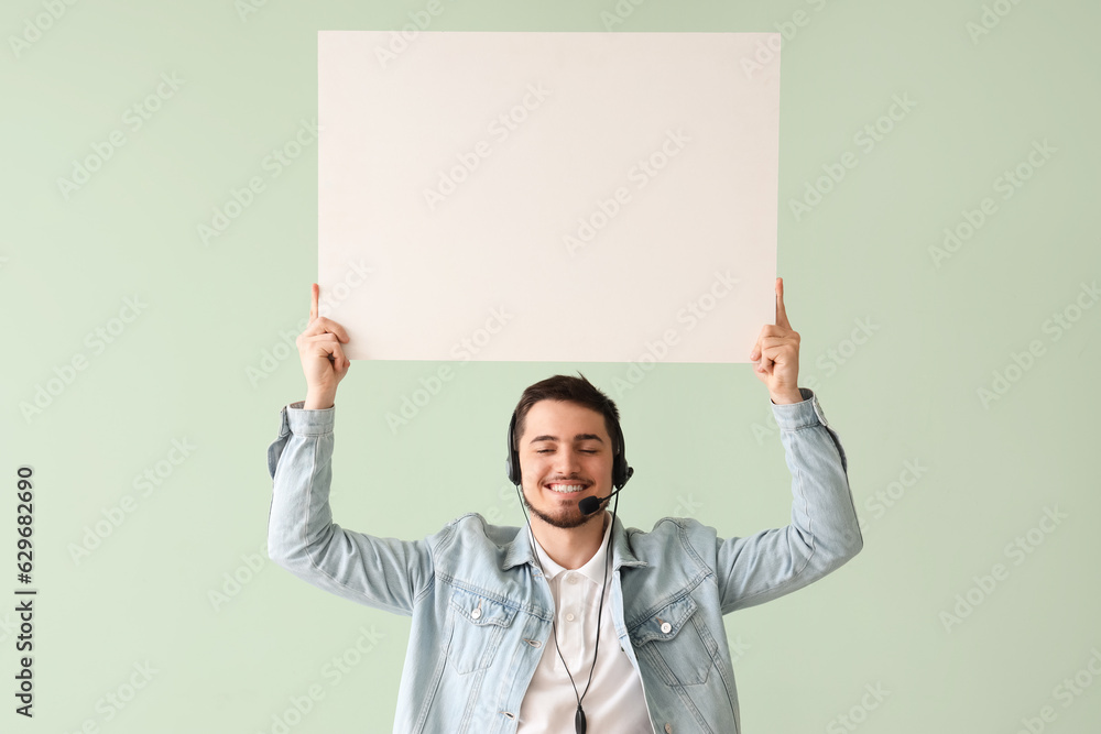 Male technical support agent with blank poster on mint background