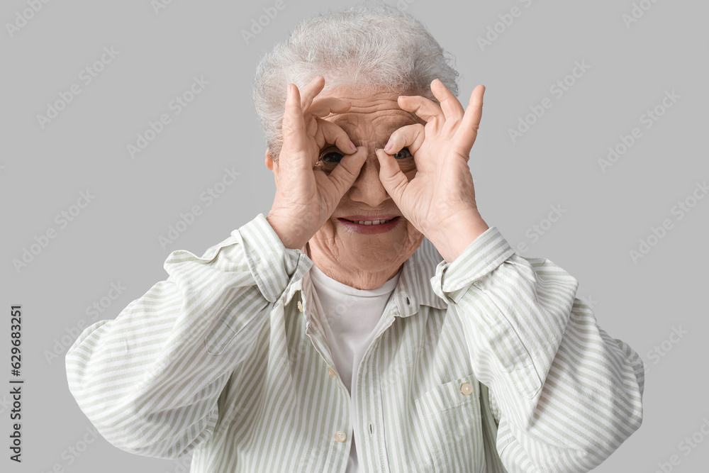 Funny senior woman on grey background