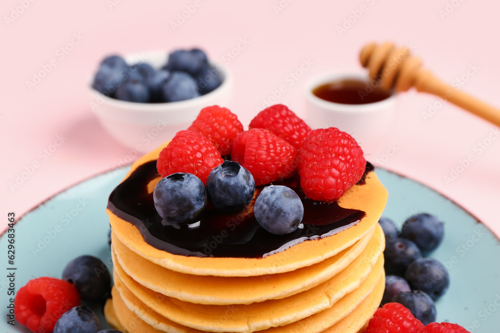 Plate with sweet pancakes and berries on pink background, closeup