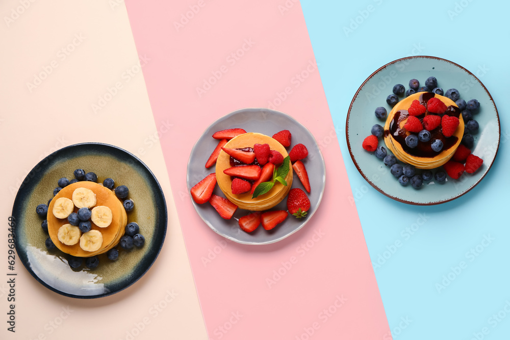 Plates with sweet pancakes and berries on color background