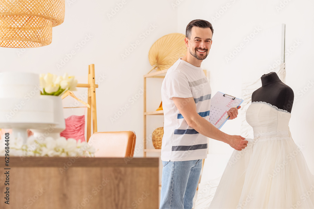 Male wedding planner working with dress in office