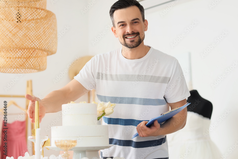 Male wedding planner working with cake in office