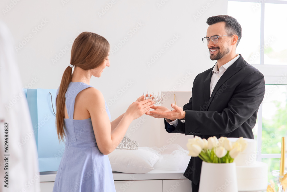 Male wedding planner showing crown to couple in office