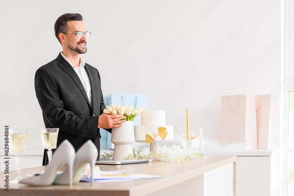 Male wedding planner with flowers in office