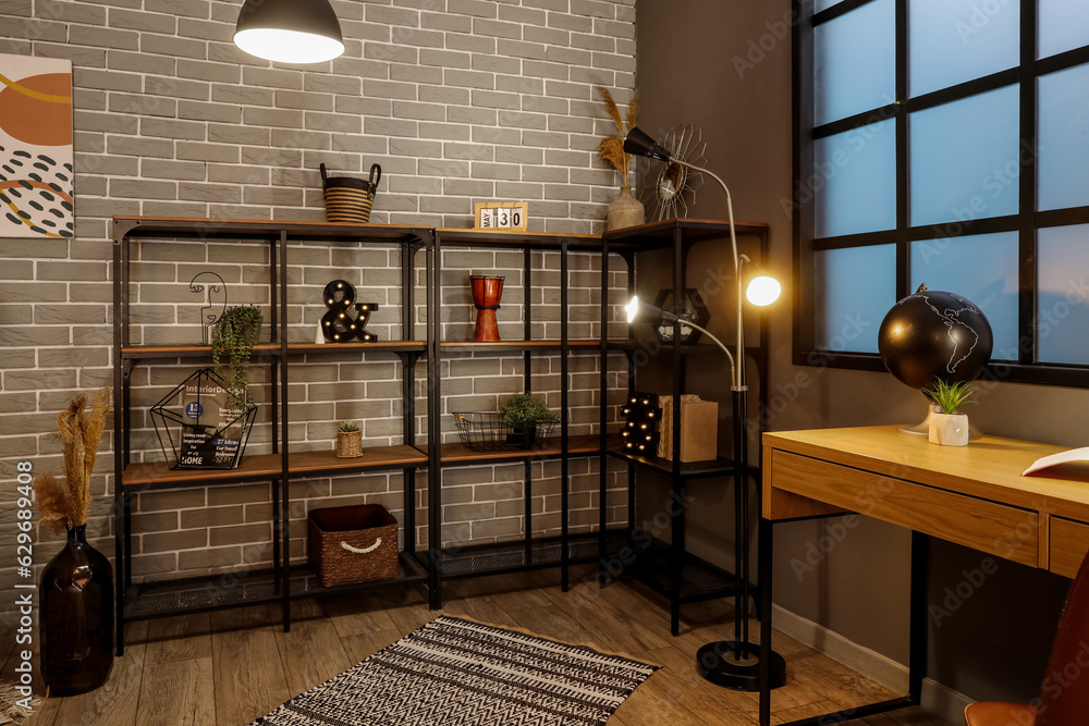 Interior of dark living room with glowing lamps and shelving unit