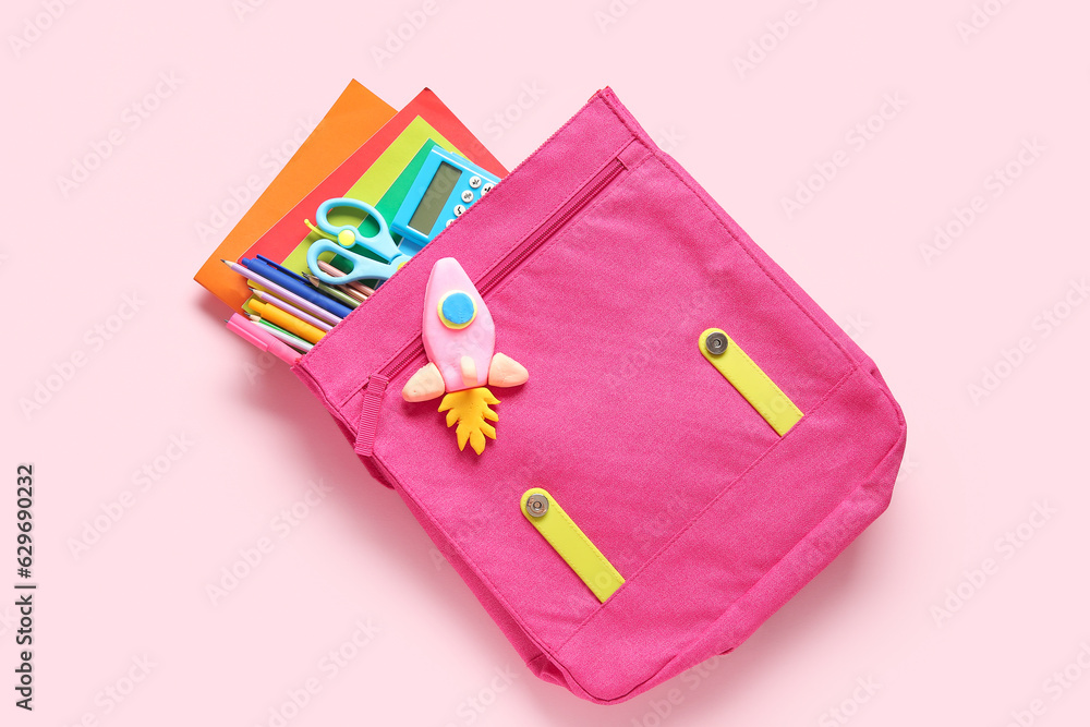 Backpack with rocket made of plasticine and stationery on pink background