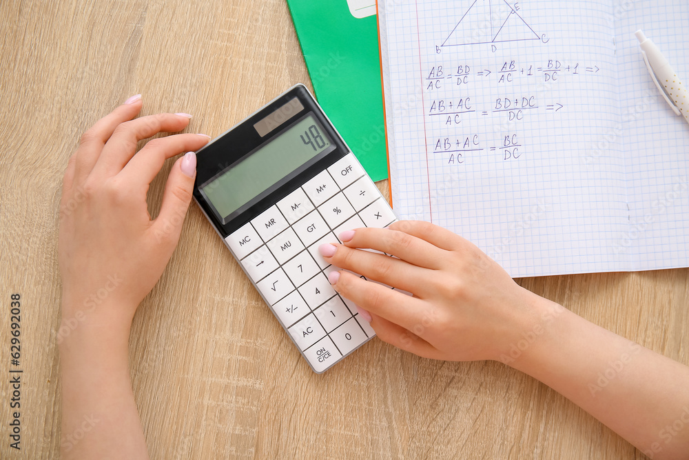 Woman working with calculator on wooden table, closeup