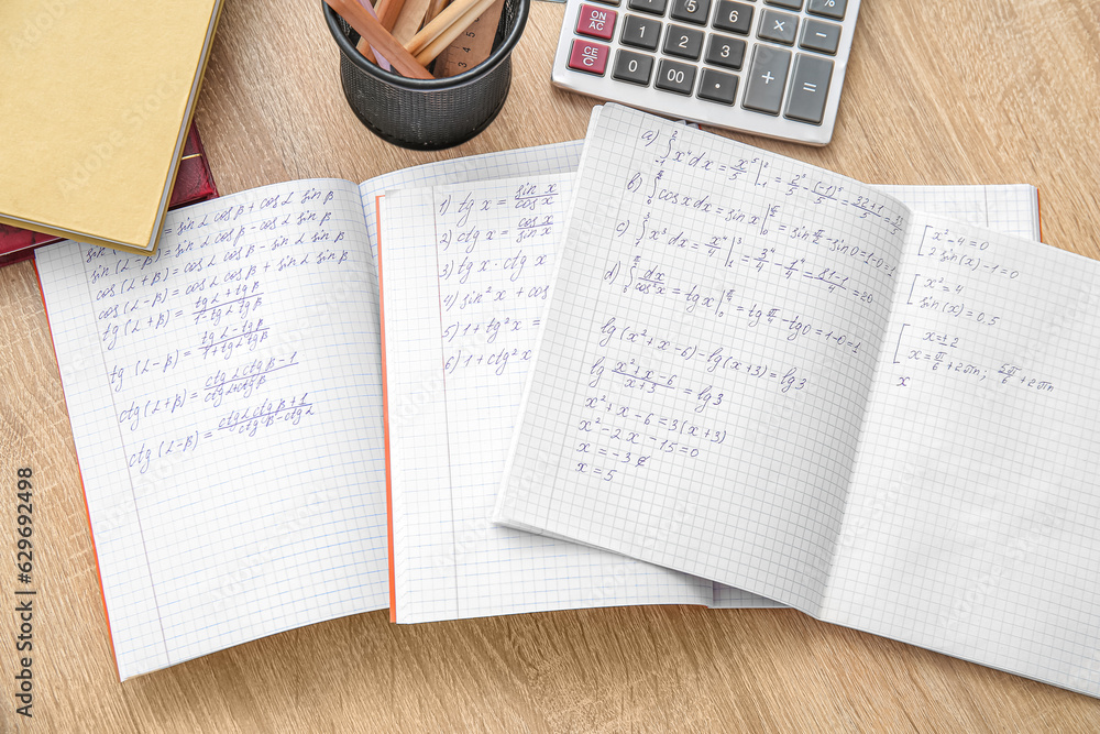 Open copybooks with math formulas on wooden table