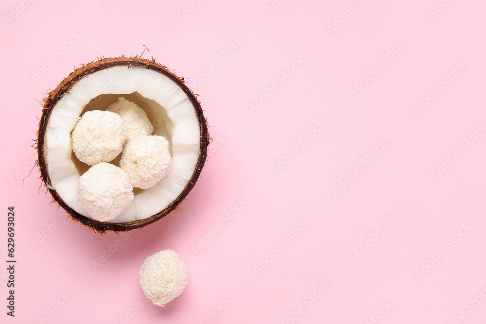 Coconut with white chocolate candies on pink background