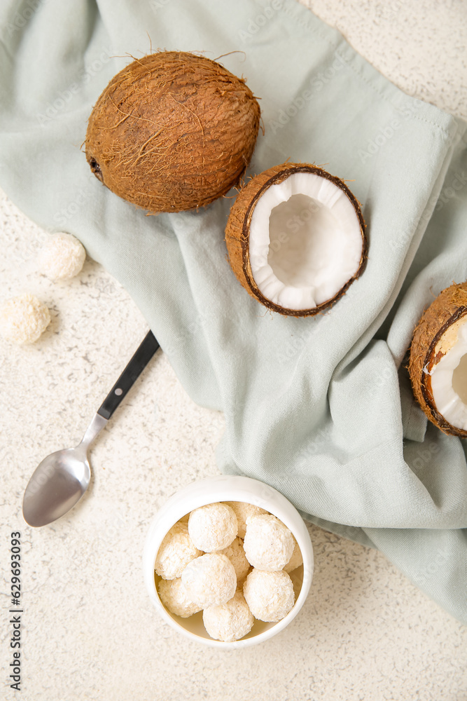 Coconuts and bowl with white chocolate candies on light table