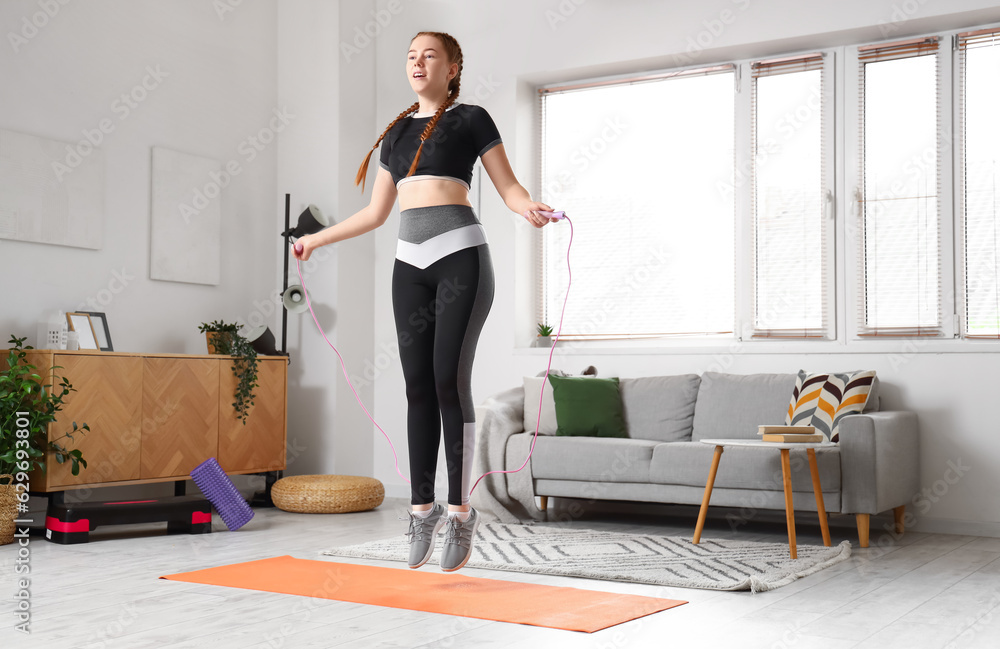 Sporty young woman jumping with rope at home