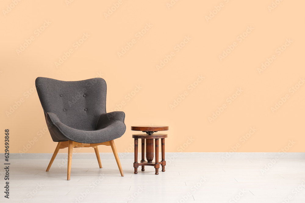 Stylish black armchair and table near beige wall