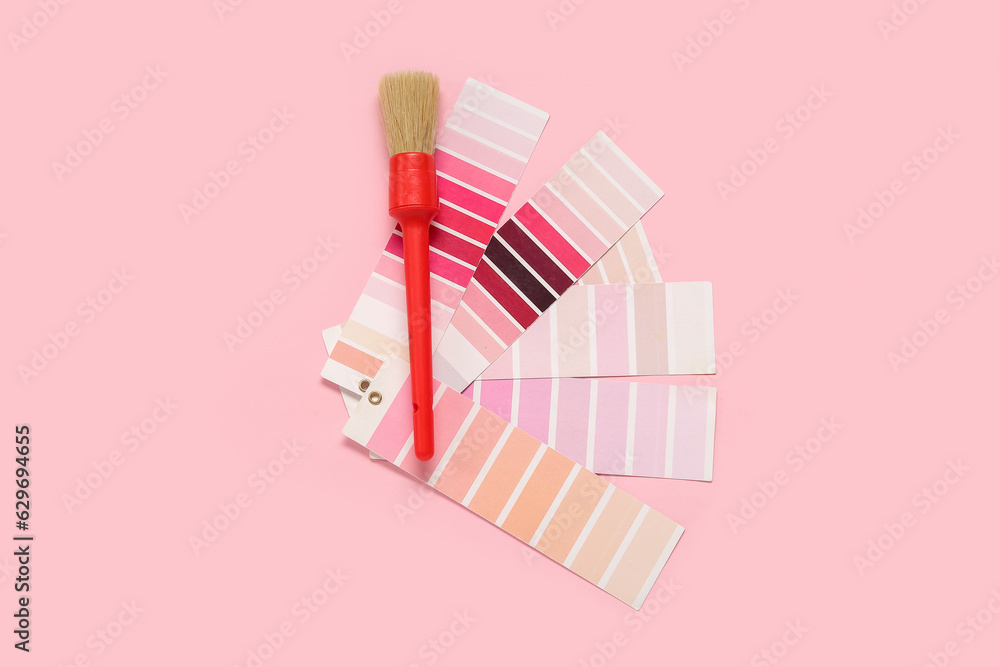 Many color palettes and brush on pink background, top view