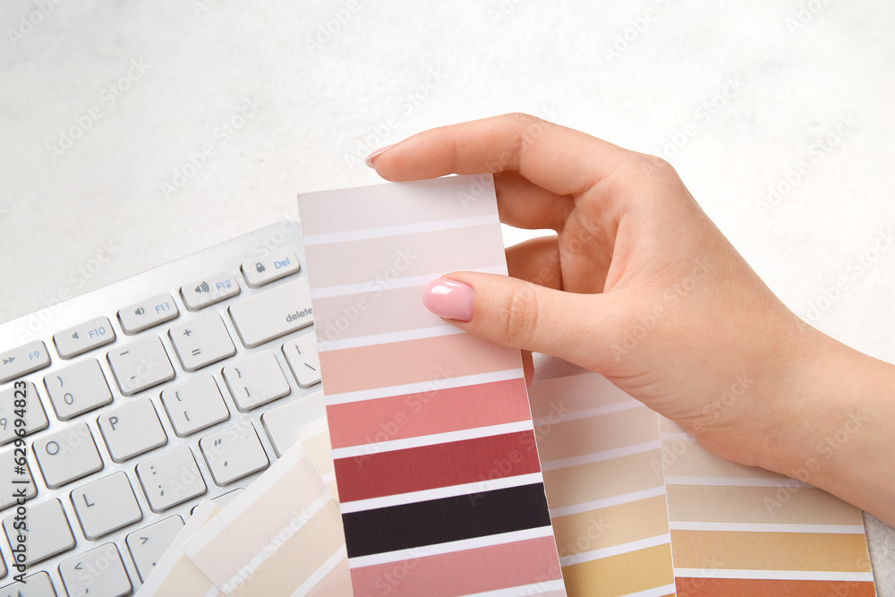 Female hand, color palettes and PC keyboard on light background