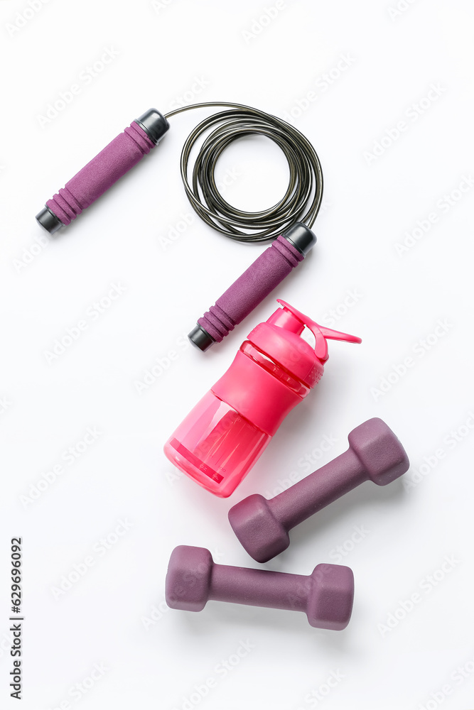 Bottle of water, dumbbells and skipping rope on white background