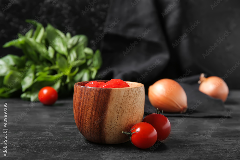 Bowl of canned tomatoes and basil on dark background