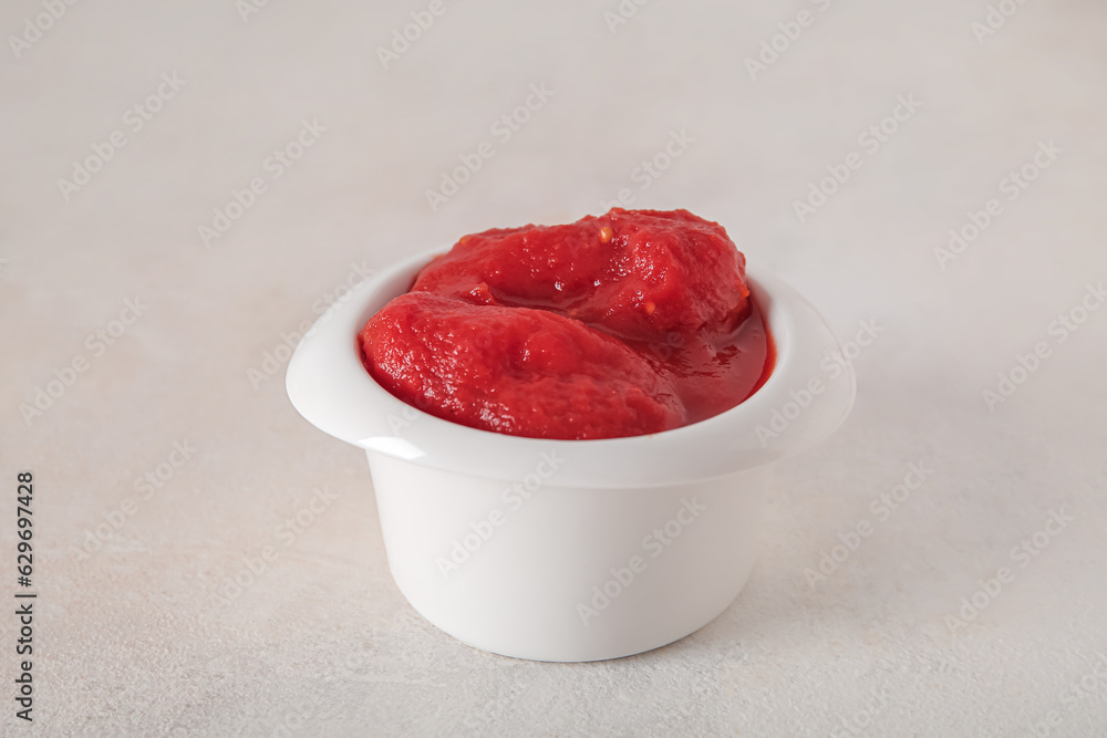 Bowl of canned tomatoes on light background