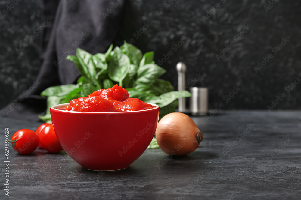 Bowl of canned tomatoes and onion on dark background