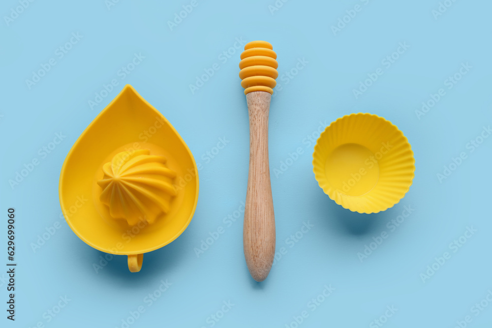 Citrus juicer, honey dipper and muffin cup on color background