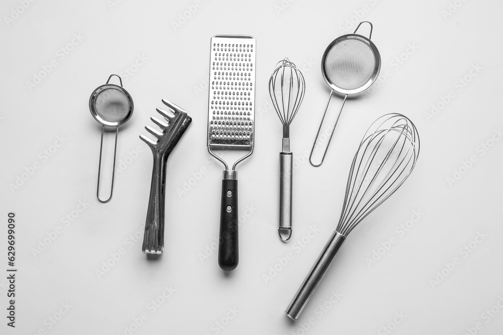 Set of stainless steel kitchen utensils on light background