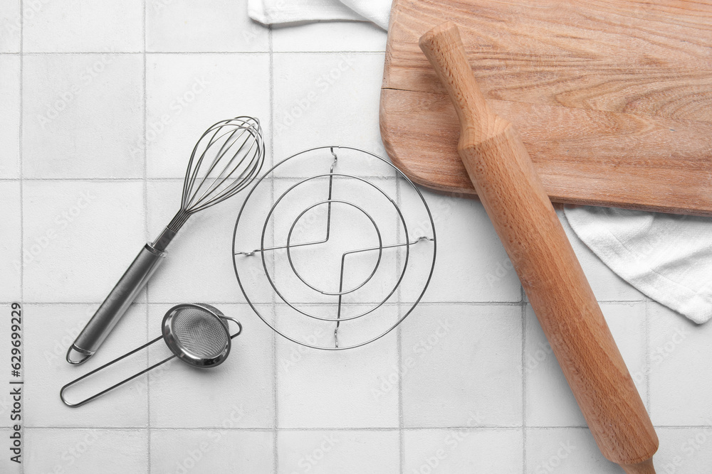 Different kitchen utensils on light tile background