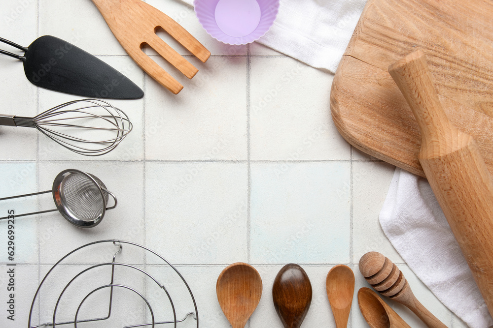 Frame made of different kitchen utensils on light tile background