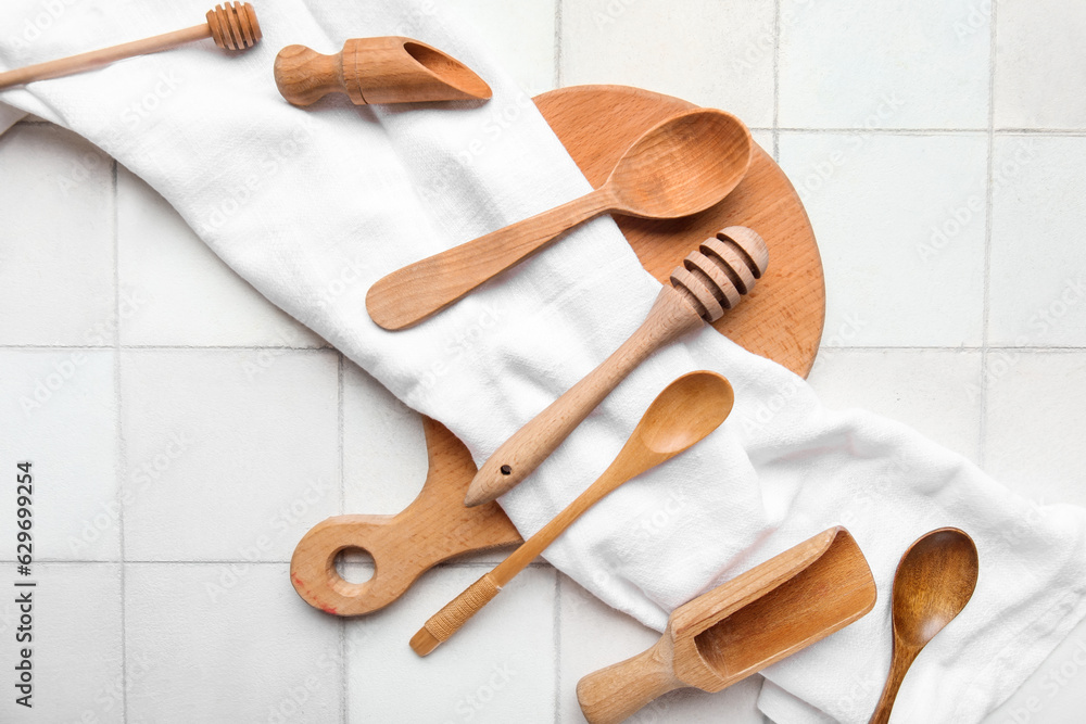 Composition with wooden kitchen utensils and napkin on light tile background