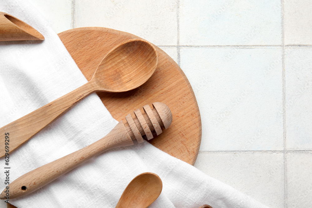 Composition with wooden kitchen utensils and napkin on light tile background