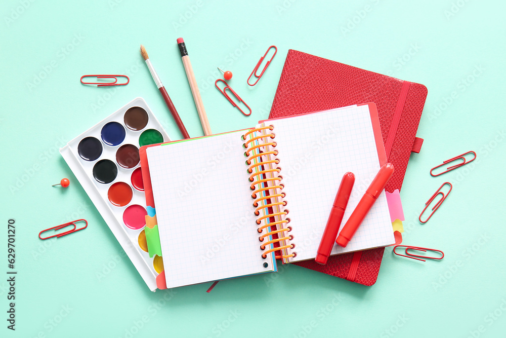 Different school stationery and notebooks on turquoise background