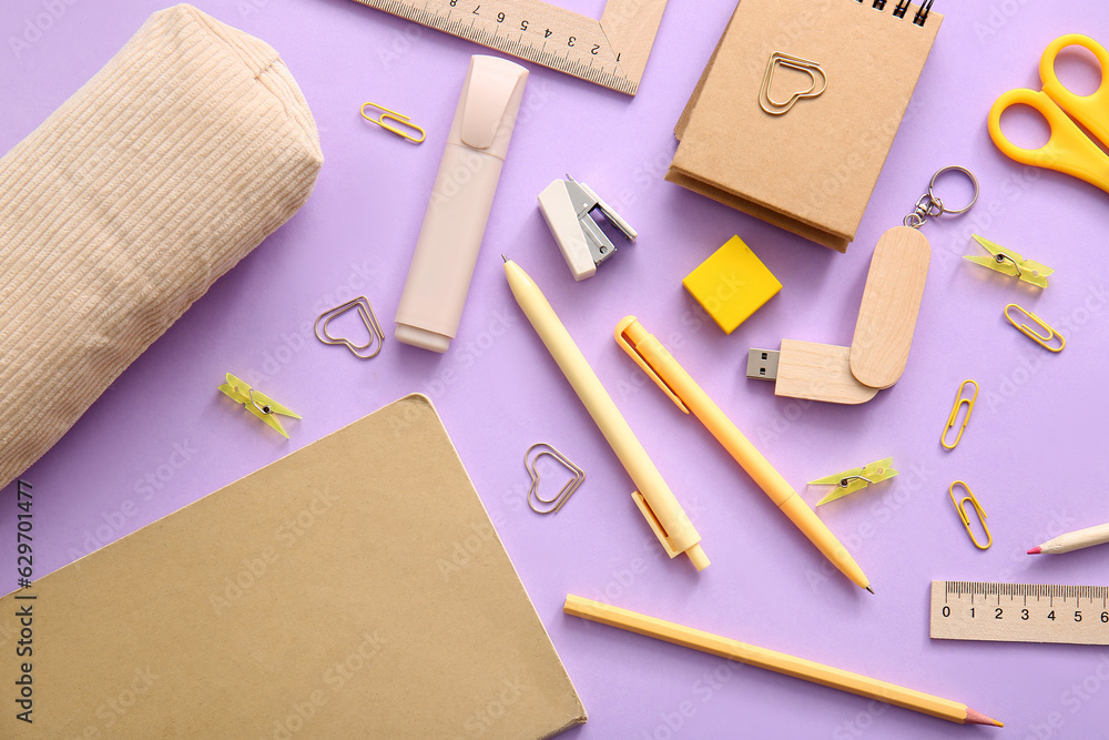 Notebooks and school stationery on purple background