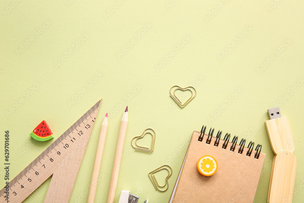 Different school stationery and notebook on green background