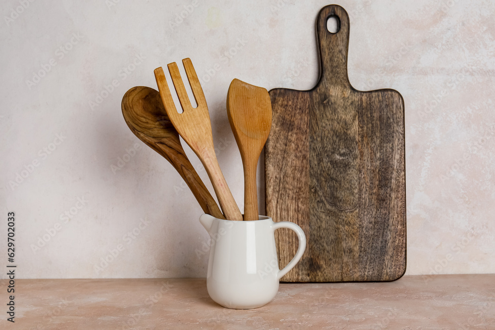 Pitcher with wooden cutlery and cutting board on table