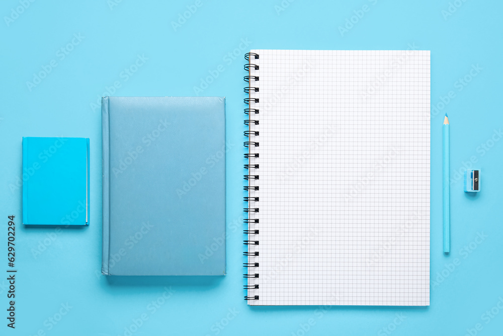 Set of notebooks, pencil and sharpener on color background