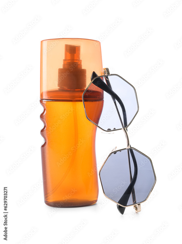 Bottle of sunscreen and stylish sunglasses on white background