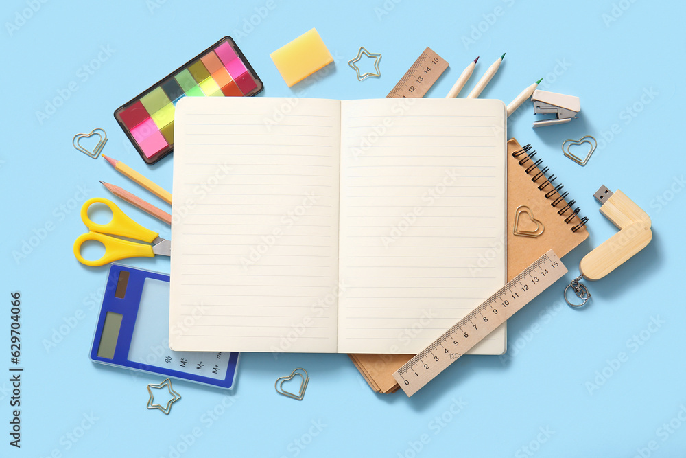 Composition with blank notebook and different school stationery on blue background