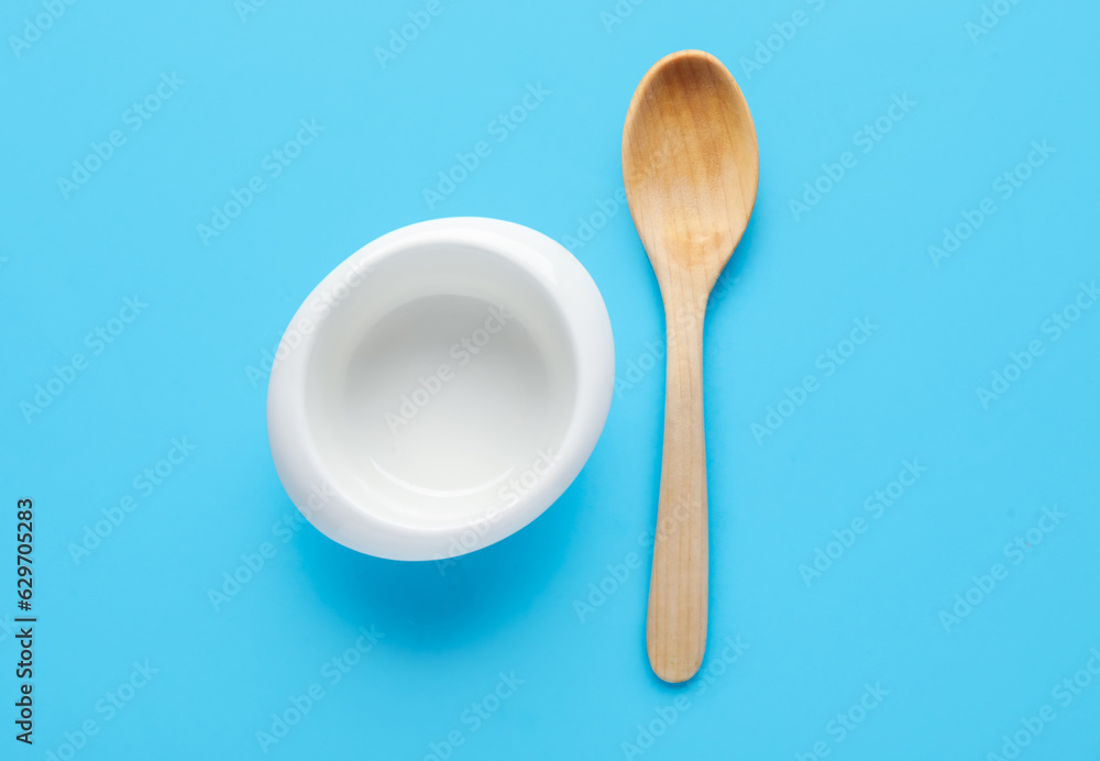 Wooden spoon and bowl on color background