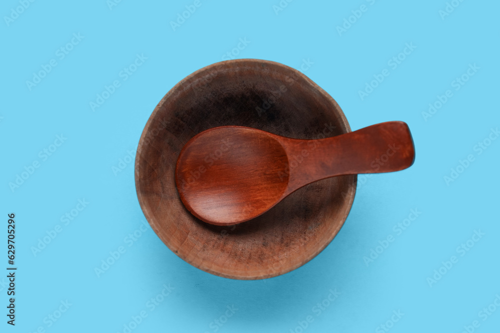 Wooden bowl with spoon on color background