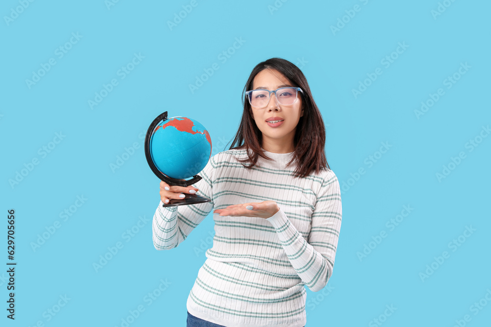 Asian Geography teacher with globe on blue background